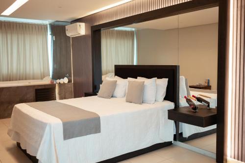 塔瓜汀加Miami Hotel by H Hotéis - Business的卧室配有一张白色大床和镜子