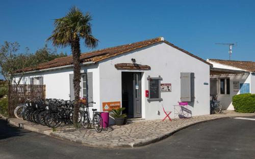 圣克莱门特德巴Camping Les Perouses的一座白色的建筑,前面有自行车停放