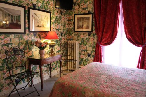 巴黎尼斯酒店的一间卧室配有一张床和一张带台灯的桌子