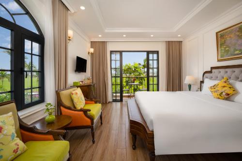 会安Maison Fleur Luxury Hoi An的酒店客房带一张大床和一把椅子