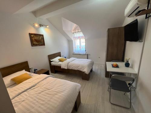 杜布罗夫尼克Apartments and Rooms Maritimo的一间卧室设有两张床、一张桌子和一个窗口。