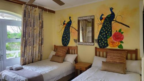 爱德华港Caribbean Estates Montego bay 30的一间卧室设有两张床,墙上设有一扇窗户,窗户上挂着孔雀。