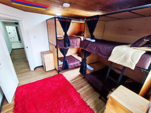 波哥大Baruch Capsula的一间设有两张双层床的客房,铺有红色地毯。