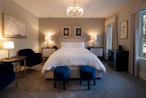 歌珊Orange Inn Boutique Hotel的一间卧室配有一张床、两把椅子和一个吊灯