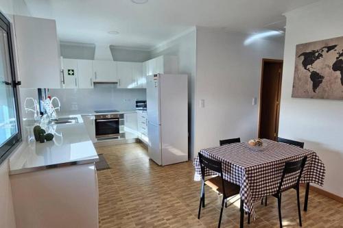 蓬塔德尔加达Casa da Relva的厨房配有桌子和白色冰箱。