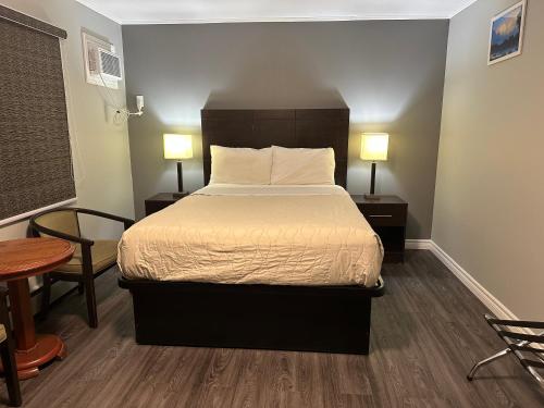 PetawawaTime Travellers Motel的一间卧室配有一张床、两张桌子和两盏灯。