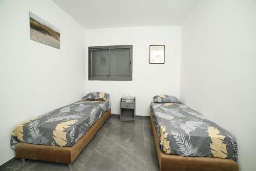 提比里亚חופשה בטבריה בבית ענק ל 8 אנשים גדול וחדש的客房设有两张床、一张桌子和一扇窗户。