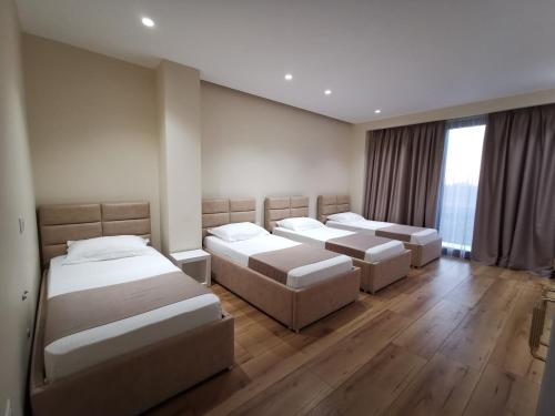 都拉斯Te Aldo Hotel的铺有木地板的客房内的三张床