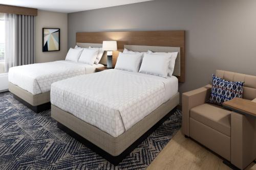 乔利埃特Candlewood Suites - Joliet Southwest, an IHG Hotel的酒店客房,配有两张床和椅子