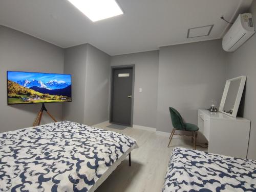 庆州Aha Stay的卧室配有一张床,墙上配有电视。