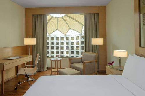 新德里新德里德瓦卡丽笙酒店的配有一张床和一张书桌的酒店客房