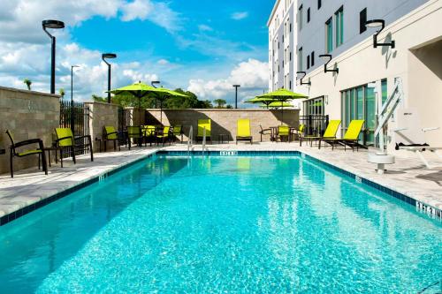 兰奥莱克斯SpringHill Suites by Marriott Tampa Suncoast Parkway的一座带椅子和遮阳伞的游泳池位于一座建筑旁边