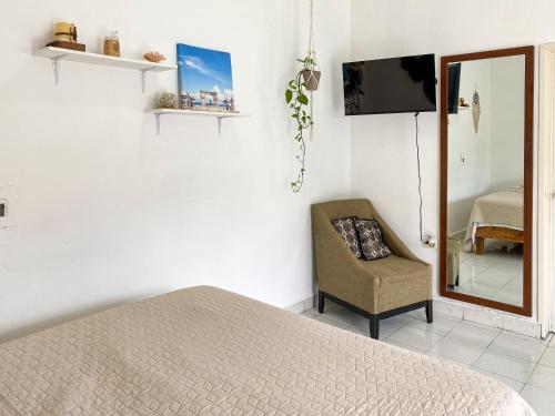 科苏梅尔Cómodo y bonito estudio en Cozumel的一间卧室配有一张床、一把椅子和镜子