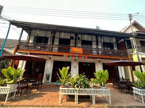 琅勃拉邦Khounphet Heritage House的前面设有桌椅的建筑