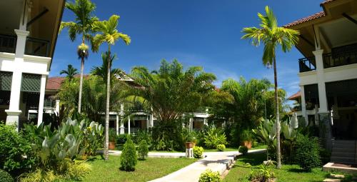蔻立Baan Khaolak Beach Resort的一群棕榈树在一座建筑前