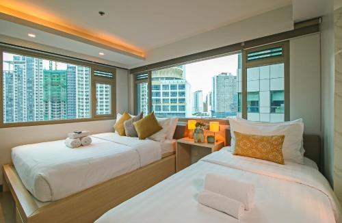 马尼拉The Mini Suites Eton Tower Makati的带大窗户的客房内的两张床