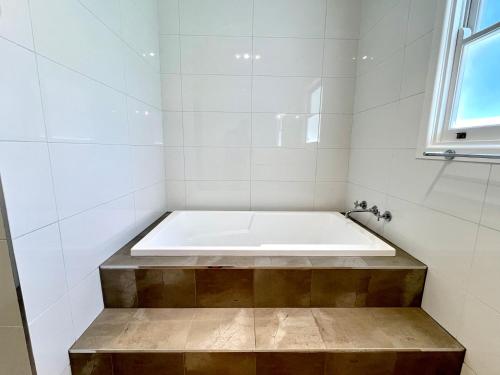 米尔迪拉Walnut House Mildura的白色瓷砖浴室内的浴缸