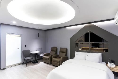 仁川市Incheon BoscoHotel的一间卧室配有一张床、两把椅子和一张桌子