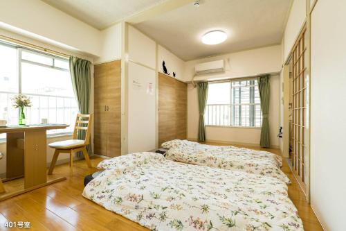 鹿儿岛Nanei Building - Vacation STAY 04859v的一间卧室设有两张床、一张桌子和窗户。