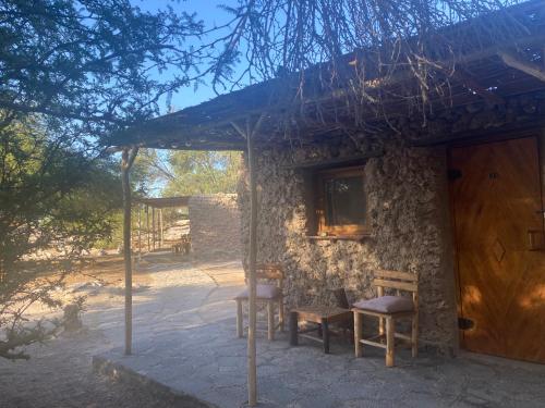 La HuaicaEl Huarango Eco retreat的石头房子,配有两把椅子和木门