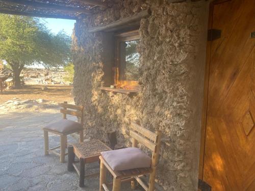 La HuaicaEl Huarango Eco retreat的两把长椅,坐在石头建筑外,有窗