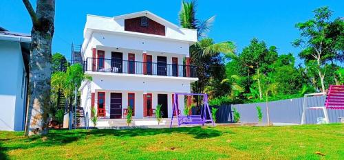 VaduvanchalThe Lavender Resort Waynad的白色的房子,有栅栏和院子