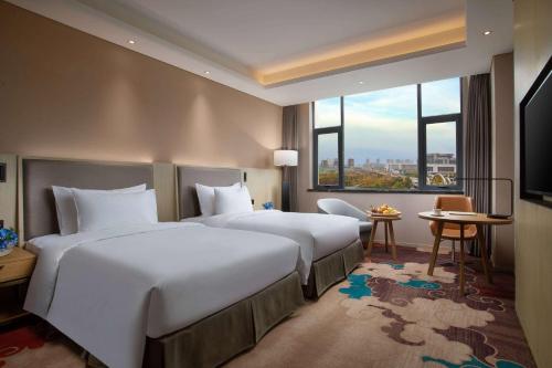 新郑郑州景瑞华美达酒店的酒店客房设有两张床和大窗户。