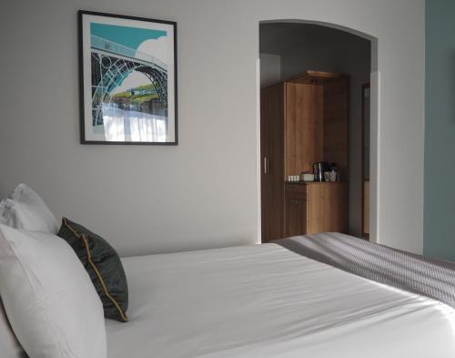 特尔福德假日特尔福德铁桥酒店的卧室配有一张白色床,墙上挂着一幅画