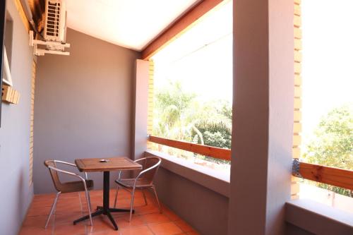 逊邱伦Casa De Jardim Guesthouse的阳台设有一张小桌子和两把椅子,并设有一个窗户