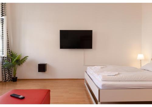 维也纳Viennese 3BR shared Apt. Near Wiener Stadthalle & Central的卧室配有一张壁挂式平面电视的床。