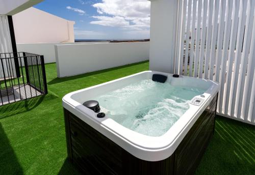 Parque HolandesShambhala Fuerteventura的一个带绿色草的阳台上的热水浴缸