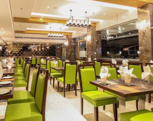 纳威孟买Hotel Vista Inn的用餐室配有绿色的椅子和桌子