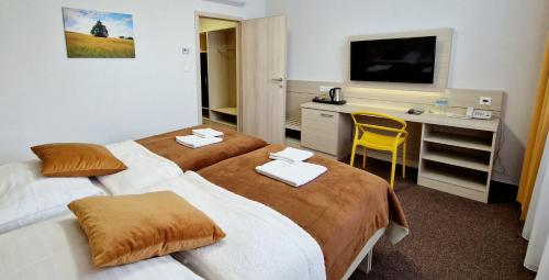 瓦赫河畔杜布尼察Hotel Kristína的酒店客房设有两张床、一张桌子和一台电视。