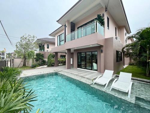 班怀雅Southern Peak Pool Villa Huay Yai Pattaya的一座带游泳池和两把白色椅子的房子