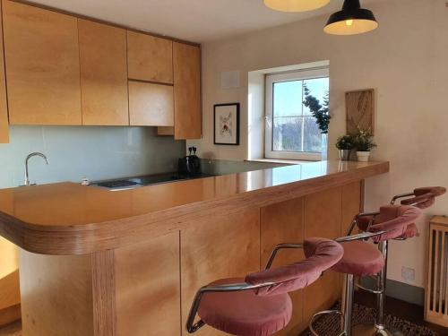 都柏林The Milltown Apartment的厨房配有带2张粉红色凳子的台面