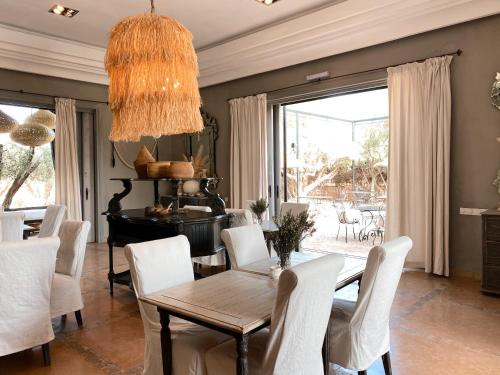 马拉喀什Villa Singulière By Louhou Collection的一间带桌子和白色椅子的用餐室