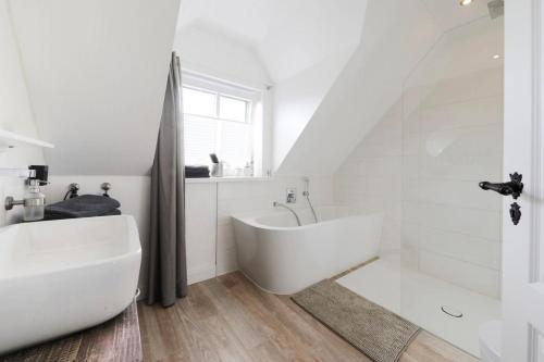汉堡Haus am Deich 47 stilvolles Landhaus an der Elbe in Stadtnähe的白色的浴室设有浴缸和水槽。