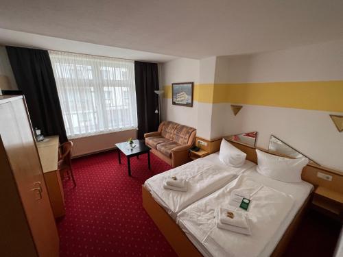 奥斯赛拜-屈隆斯博恩Hotel Poseidon的酒店客房,配有床和沙发