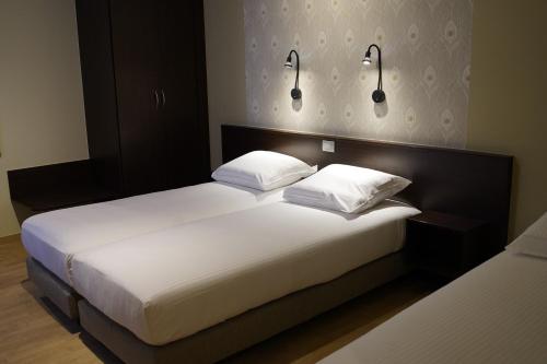 布兰肯贝赫Hotel Corner House by WP Hotels的一间卧室配有两张床,墙上有两盏灯