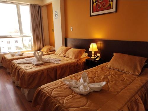 塔克纳Hotel Dubái的两张位于酒店客房的床,配有毛巾