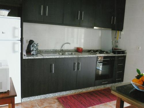 BesteirosCasa Quelhas的厨房配有黑色橱柜、水槽和冰箱。