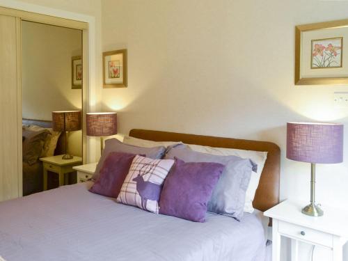 卡博斯特Fernilea Cottage的一间卧室配有一张带紫色枕头的床