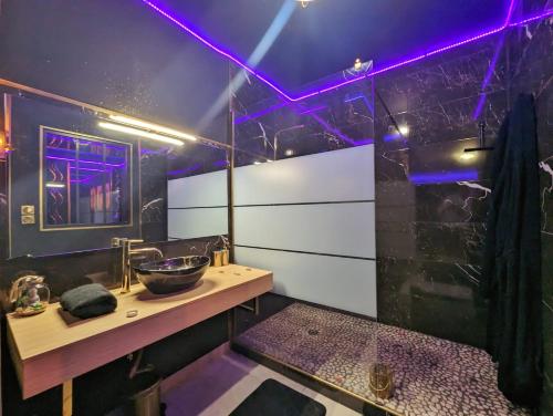 佩皮尼昂Suite Romantique Jacuzzi & Sauna privé Full options TV的一间带水槽和紫色灯的浴室