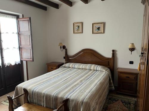 ToñanesPosada San Tirso的一间卧室配有带条纹棉被的床和窗户