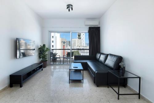 尼科西亚Urban Condo 12 - 2 Bdr的一间带黑色沙发的客厅和一个阳台
