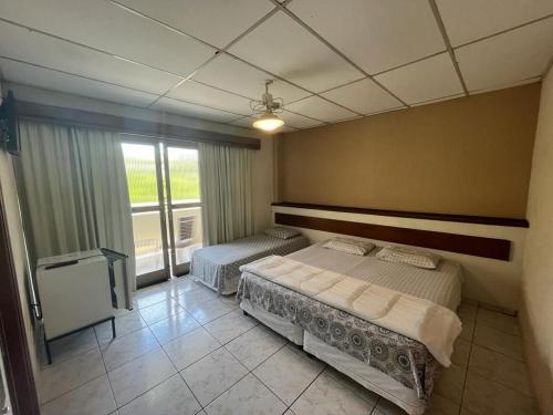 塞拉内格拉Travessa 12 - Suítes centro de Serra Negra - SP的一间卧室设有两张床和窗户。