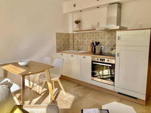 旺斯La Reposée, bas de villa en plein cœur de Vence的厨房配有白色橱柜、桌子和用餐室。