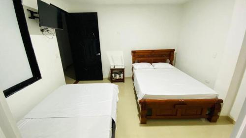 阿瓜奇卡Hotel Villa Paraguay的小客房内的两张床,配有白色床单