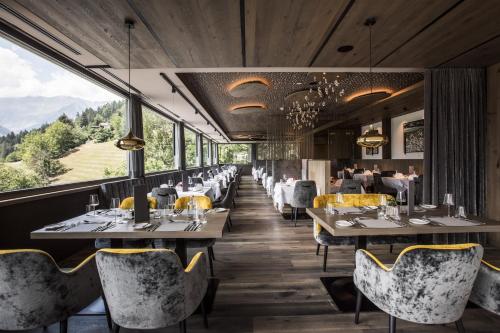 圣莱奥纳尔多因帕西里亚Hotel Bad Fallenbach的餐厅配有桌椅,位于山脉的背景中