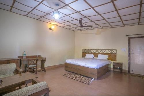 塔拉Maharaja Kothi Resort, Bandhavgarh的一间卧室配有一张床、一张桌子和一张桌子